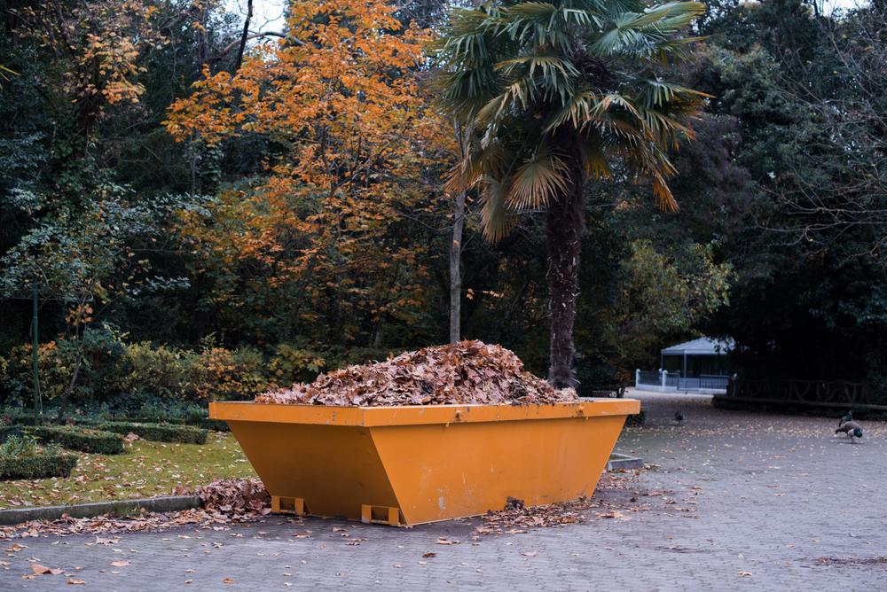 Large,Yellow,Metal,Container,Full,Of,Fallen,Leaves,In,A