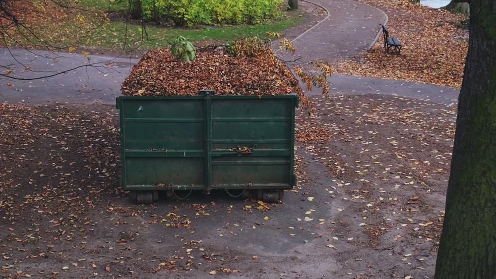 Full,Dumpster,Container,Filled,With,Yellow,And,Brown,Withered,Leaves